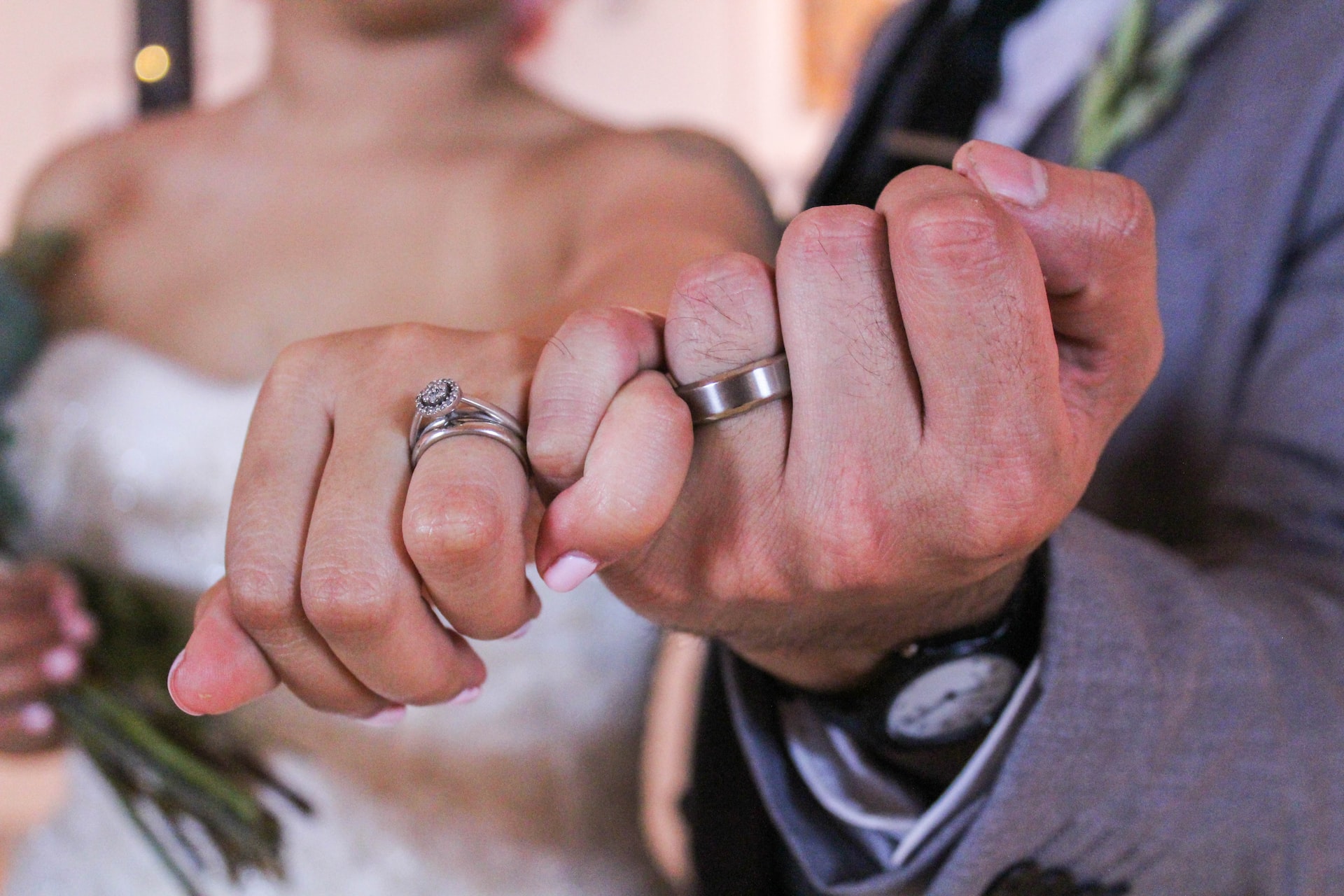 A bride and groom holding out their hands with their wedding rings